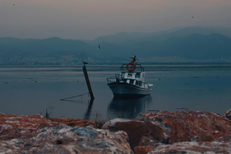 a boat sits in the water with mountains in the distance