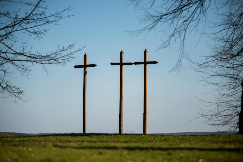 cross on hill overlooking tree lined landscape under blue sky