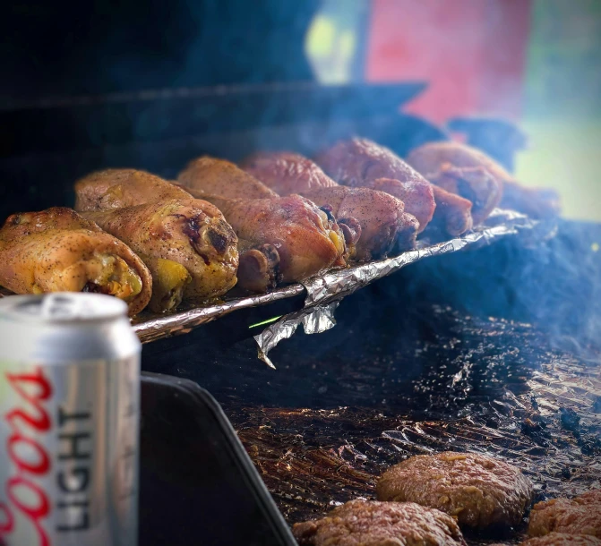 meat is cooking on an open grill with coke