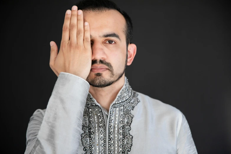 a man in a dress shirt holding his hands near his face