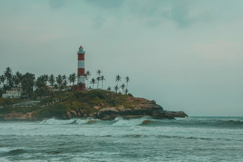 an island with a light tower and palm trees on top