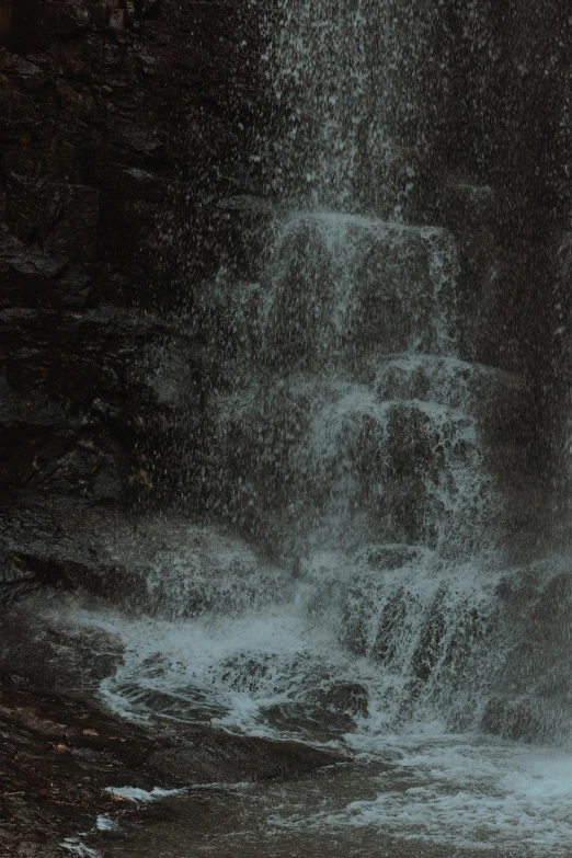 a woman under an umbrella is standing in front of a large wave