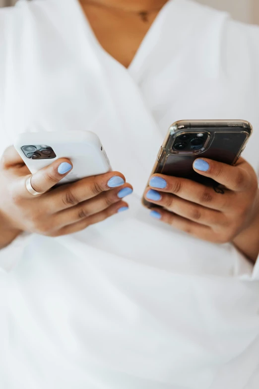 a woman in a white shirt holding two phones