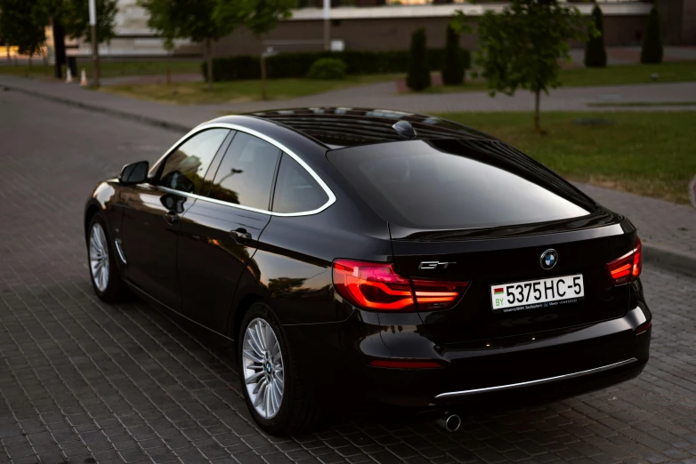 the back end of a black bmw parked in front of an empty lot