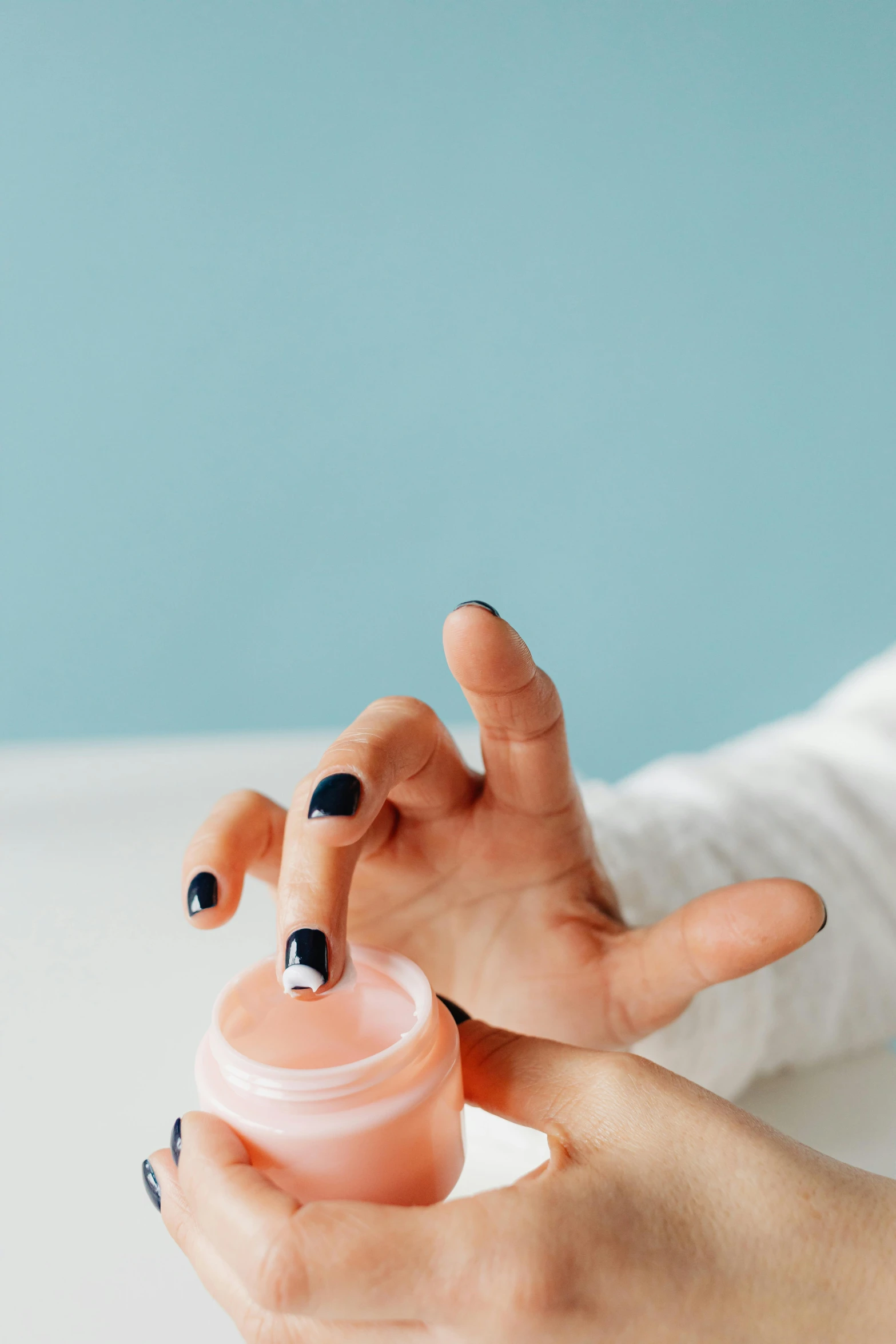 a woman holding up her fingers and a lip balm bottle