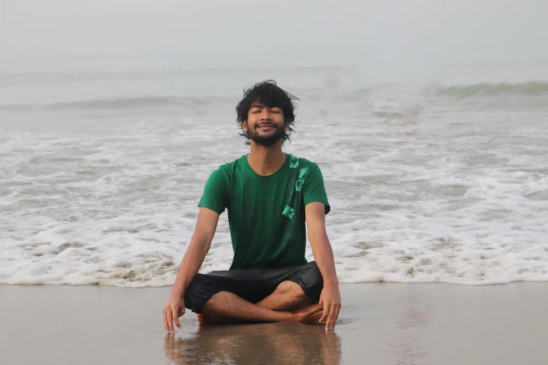 a man sitting on the beach while meditating