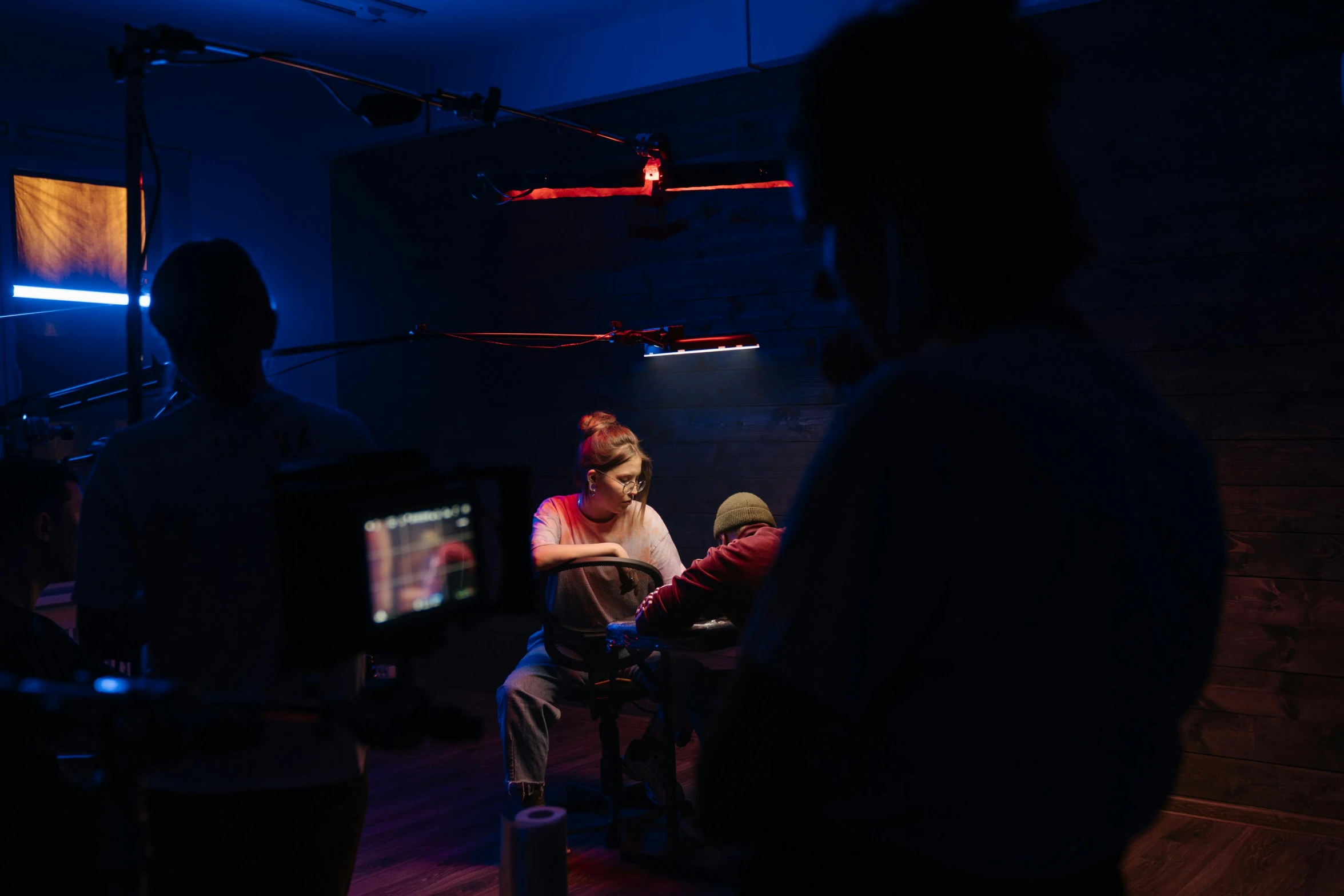 three people standing and sitting around in the dark