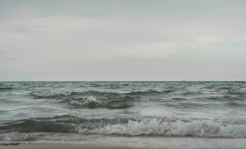 a rough beach with lots of waves coming in