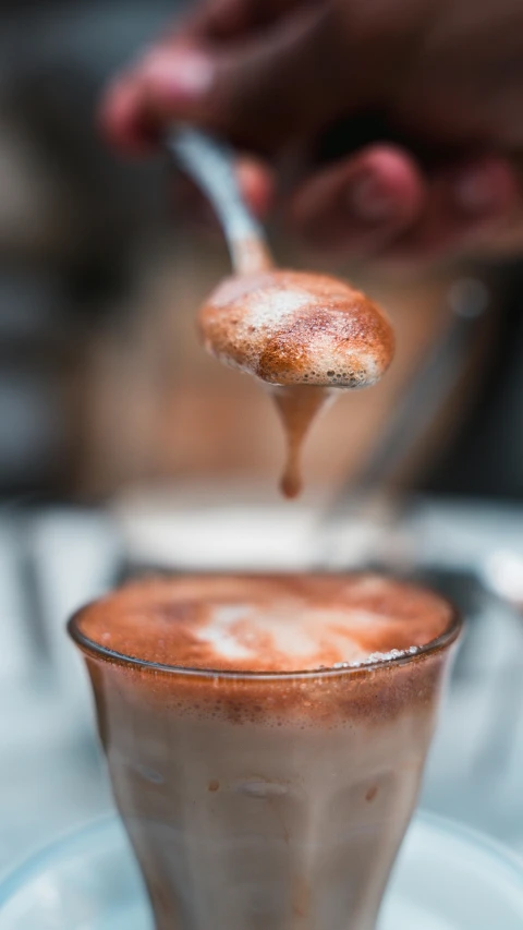 a spoon with some food in it in a small glass