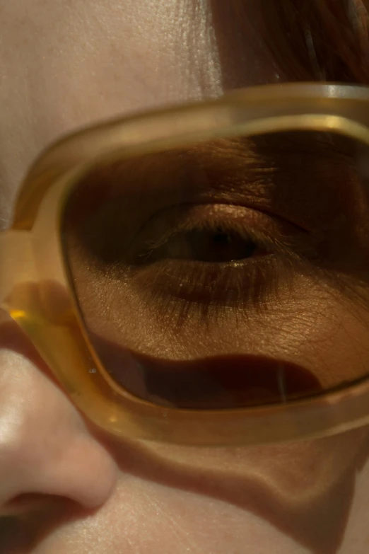 a woman's face is reflected with a pair of brown and yellow goggles