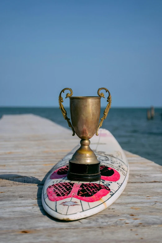 an old gold trophy sitting on a white surfboard