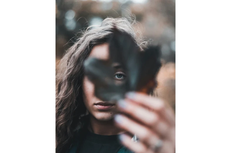 a girl looking out through a leaf through a pair of hands