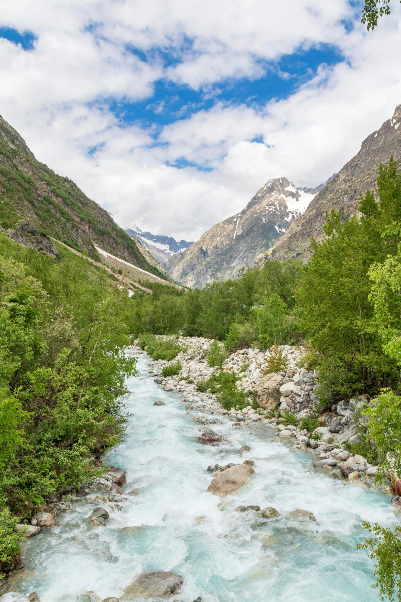 a rocky river near mountains and green trees