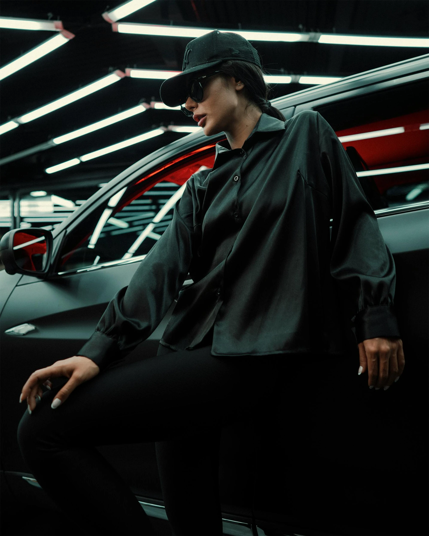 a woman sitting on a ledge next to parked cars