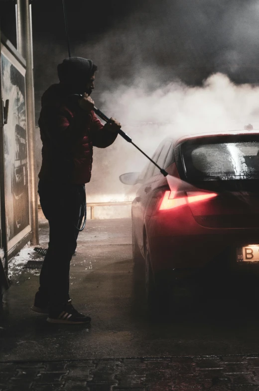 the man is using a steam wand on a car