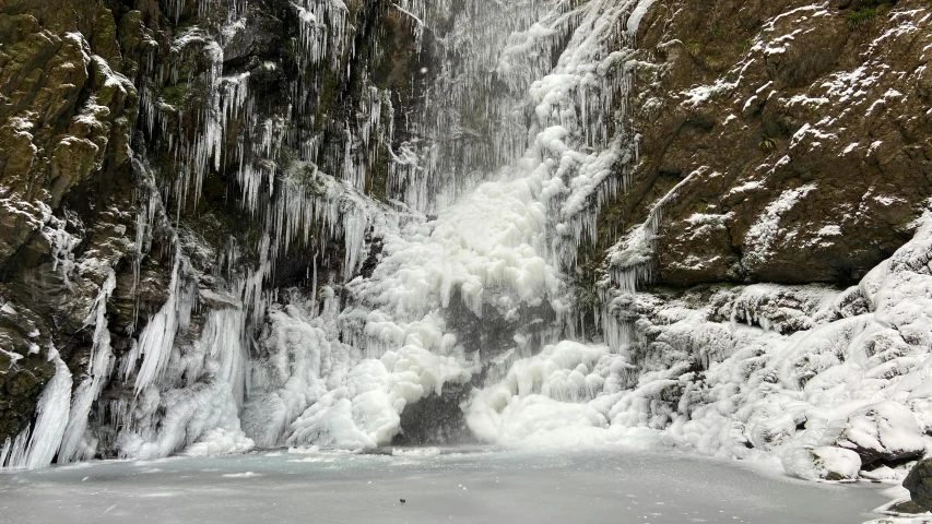 a big waterfall next to some very snowy mountains