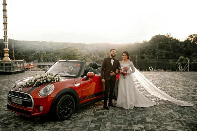 a bride and groom standing next to their convertible car