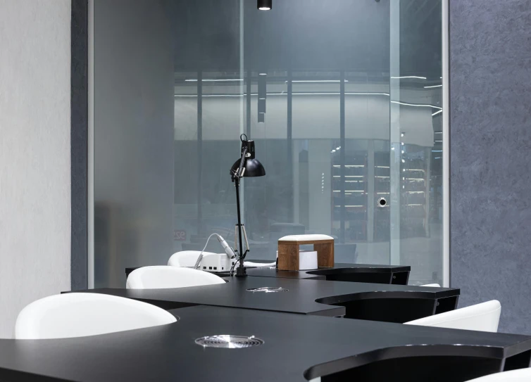 a table with black chairs sits under a glass wall