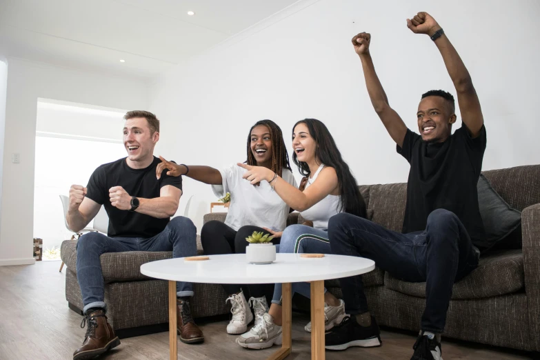 four people posing with their fists in the air in front of a white table