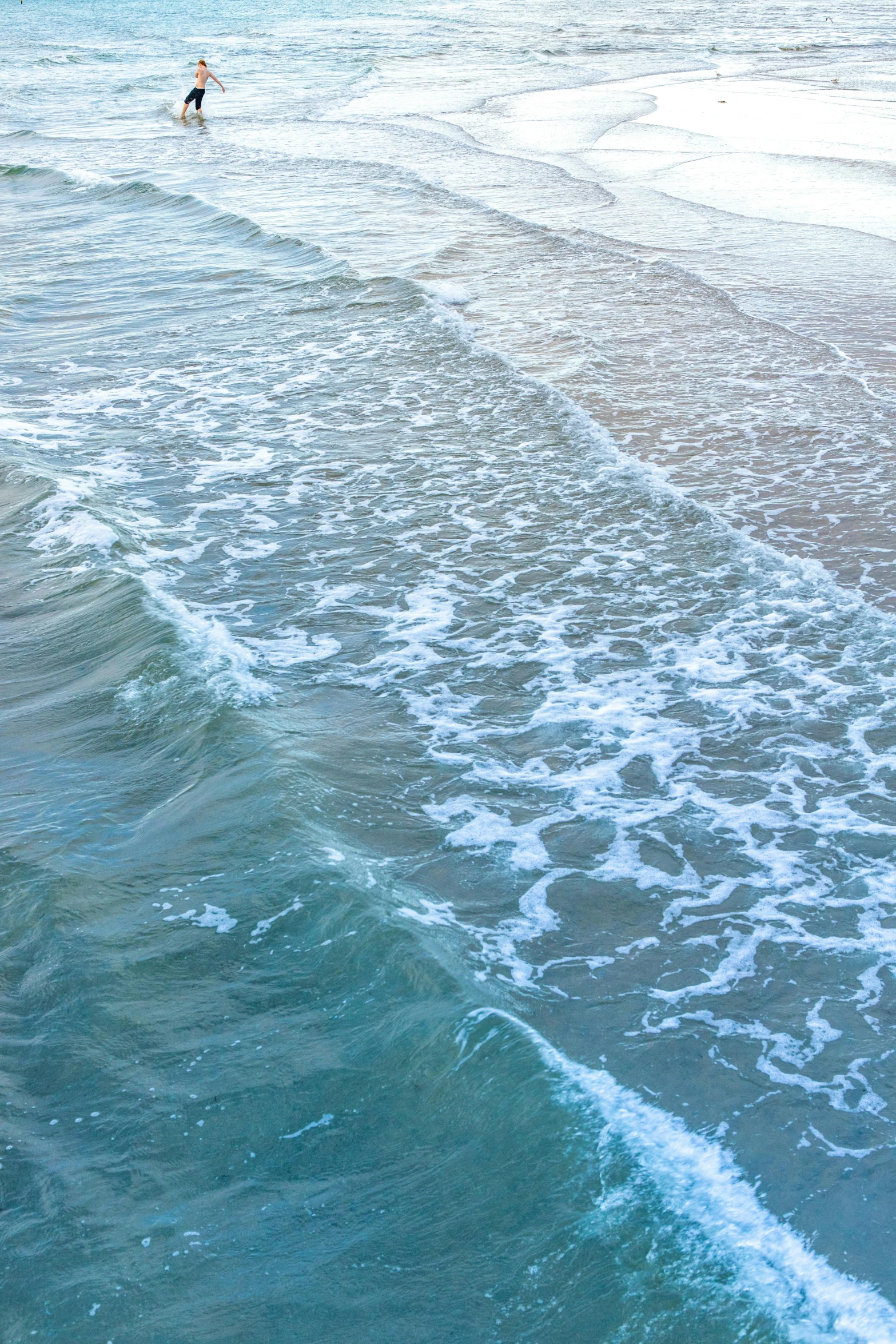 the water is crashing and surfers are in the distance