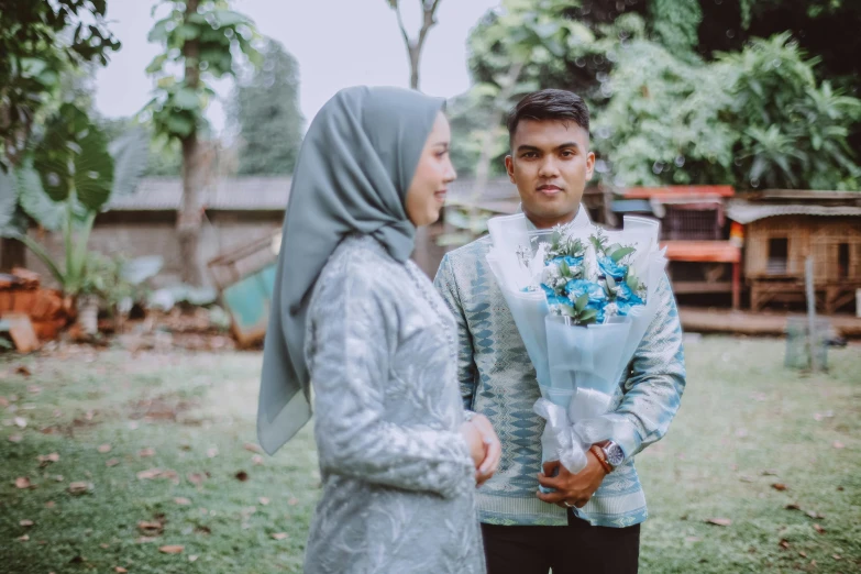 a man wearing a veil and flowers on his chest holds his bride's bouquet