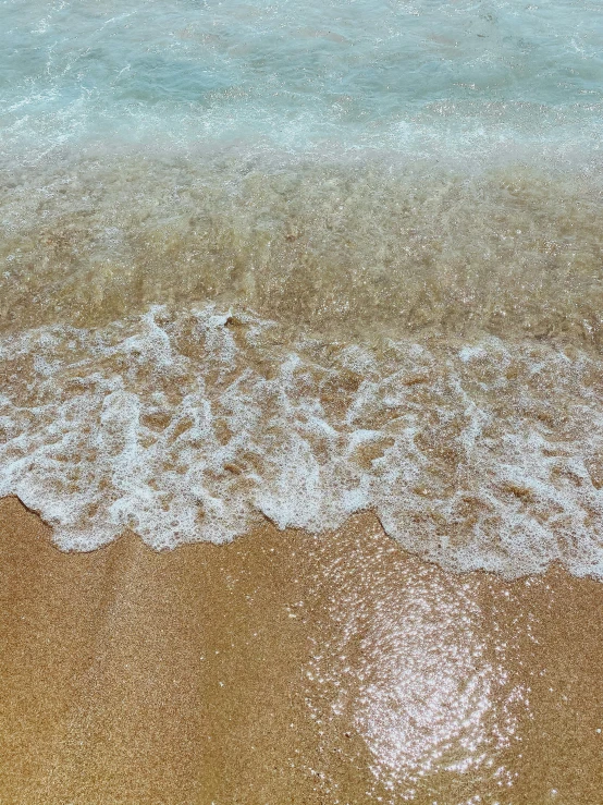 a beach is seen with waves rolling over and the sand is soft