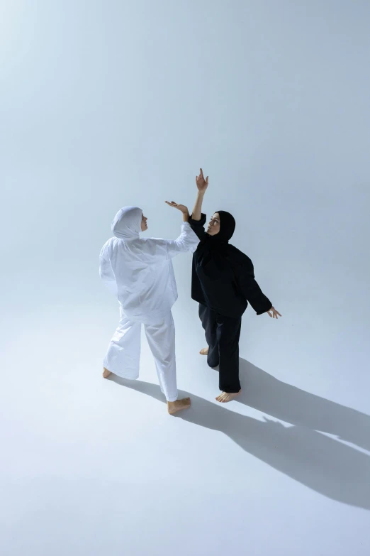 two people dressed in white and black are pointing with each hand