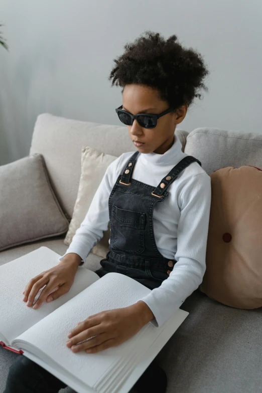 a black woman sitting on a couch and reading a book