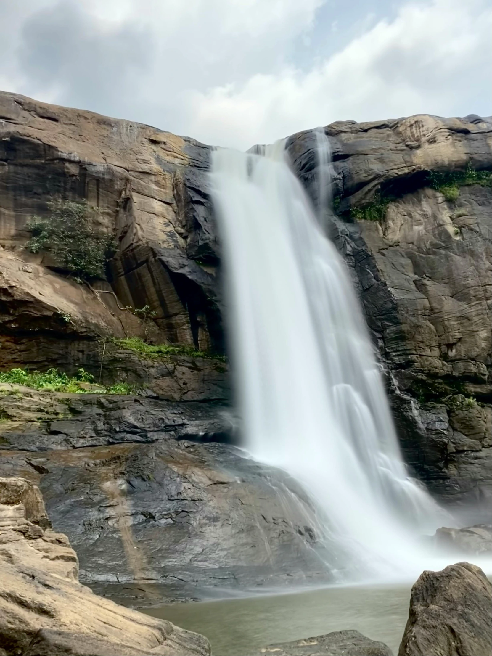 a group of rocks sitting under a waterfall