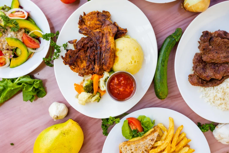 a group of plates of food containing meat and vegetables