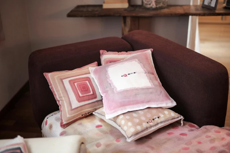 a set of four pillows sitting on top of a brown couch