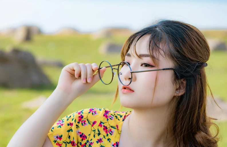 a woman wearing glasses standing in the grass