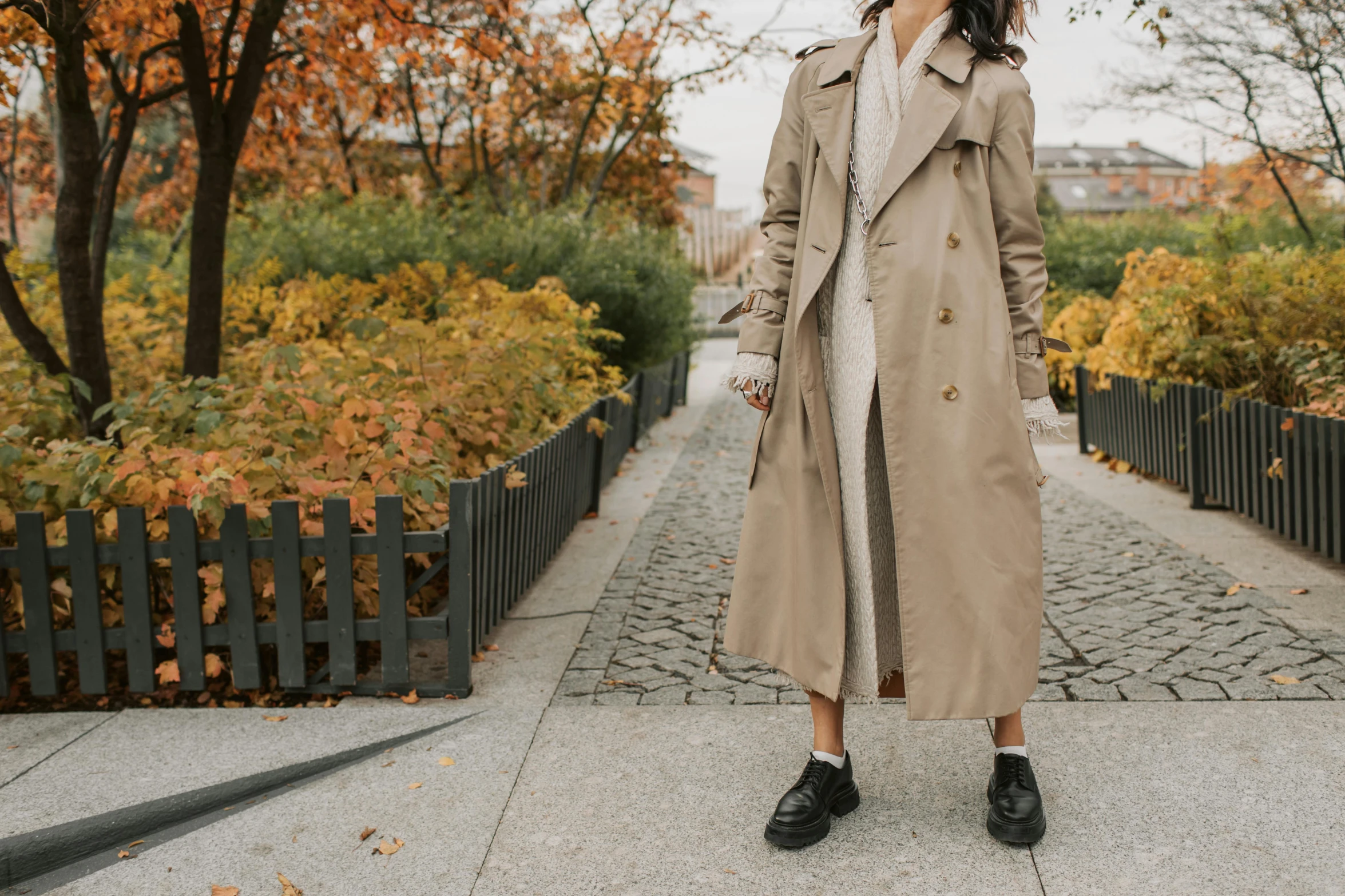 the girl stands on a paved walkway in front of a tree