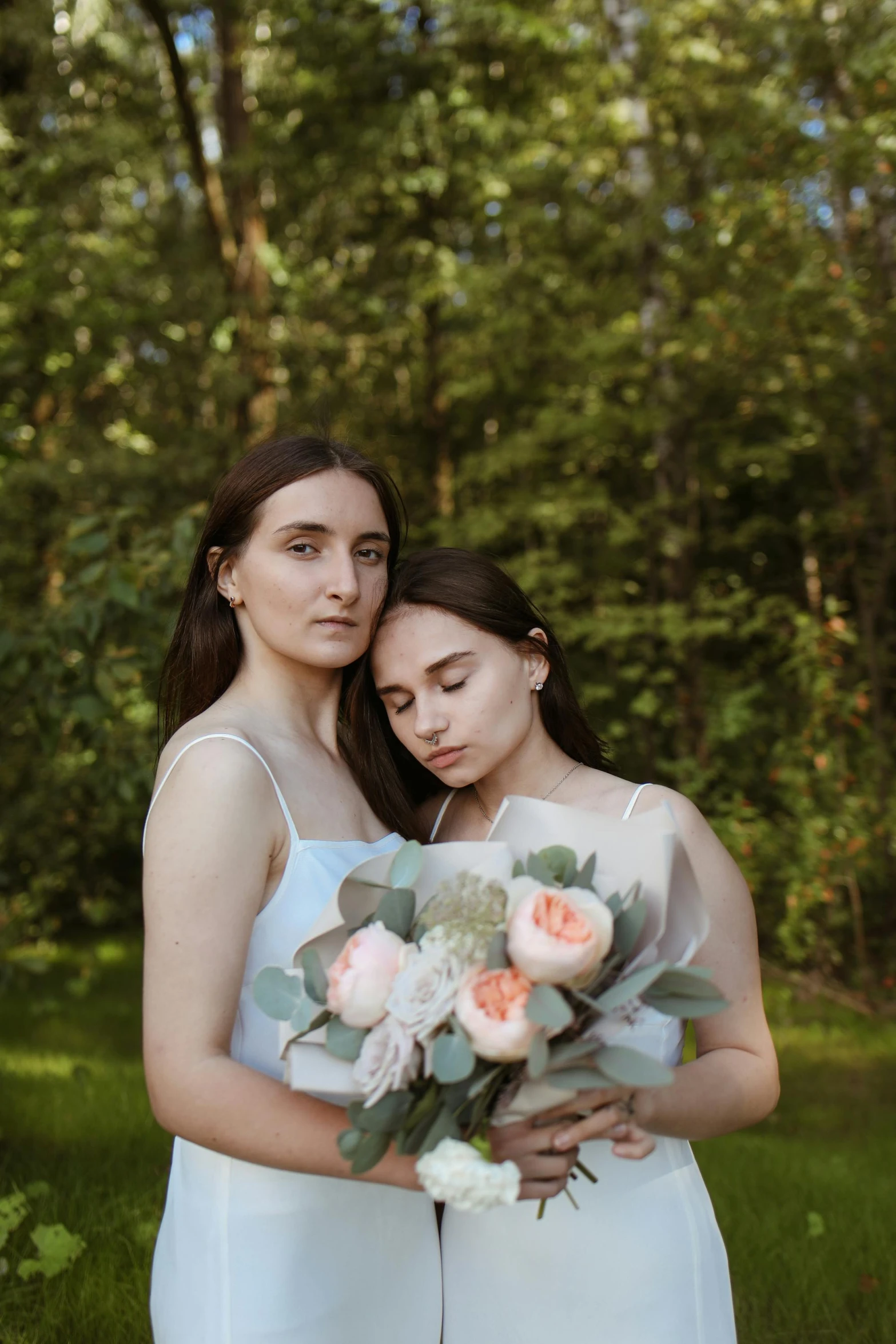 two beautiful brides pose for a wedding pograph in their yard