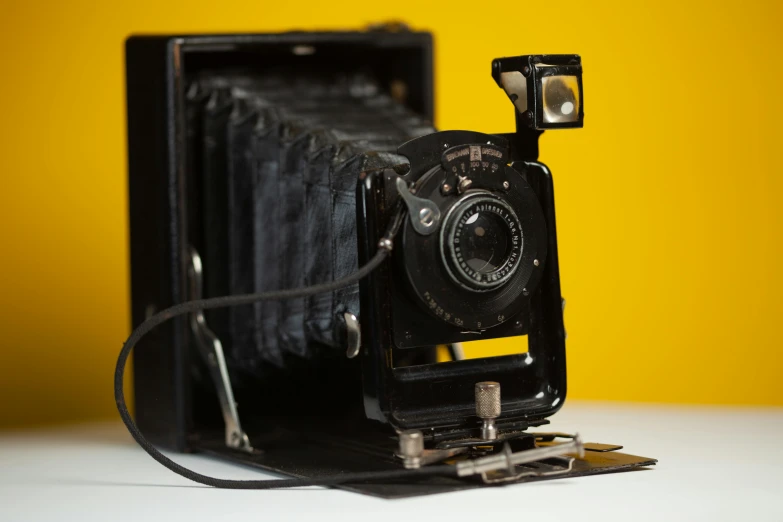 an old camera that is attached to a yellow background