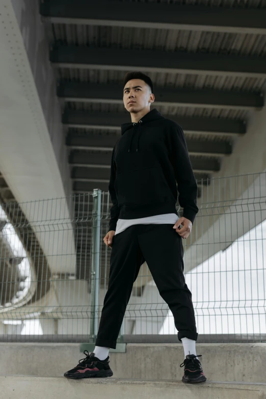 a young male with a black hoodie and pants standing by some stairs