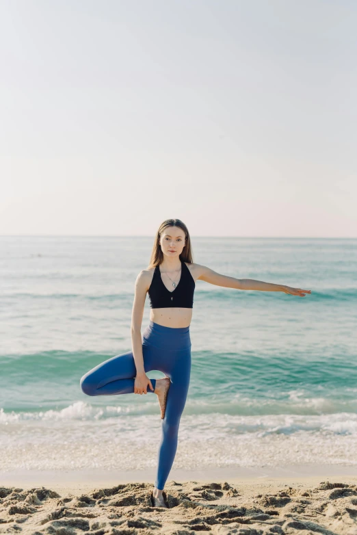 a woman doing yoga by the water in a black top