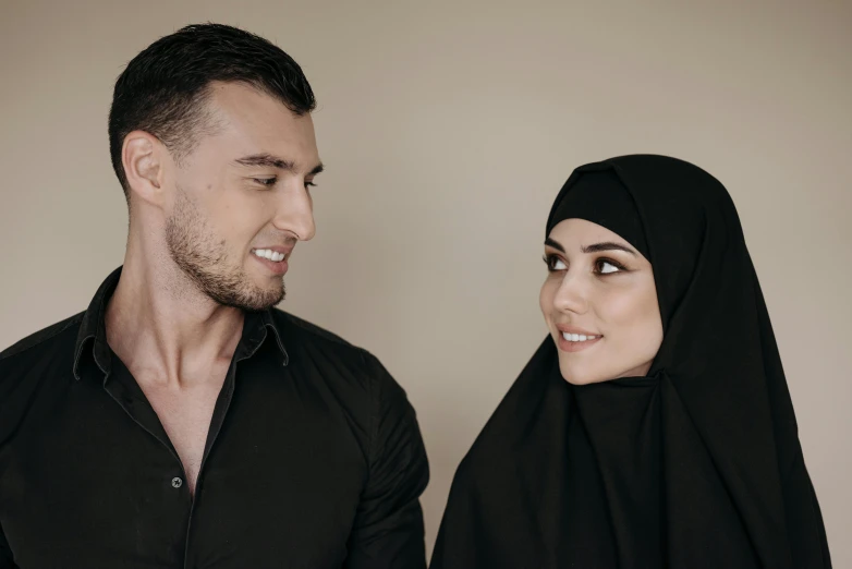 a man and woman in black clothing pose for the camera