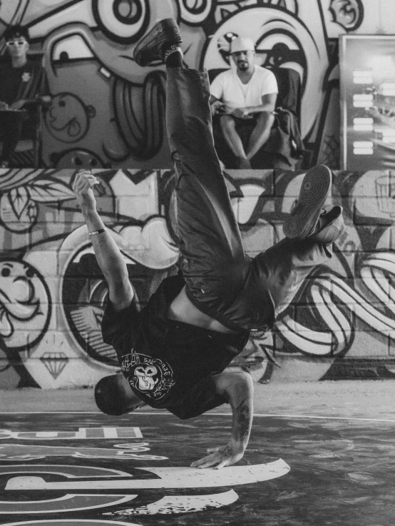 a man doing a handstand on his skateboard with graffiti on the walls behind