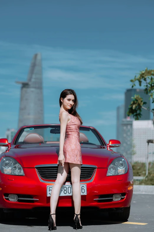 the woman leaning against the parked red car is posing for a picture