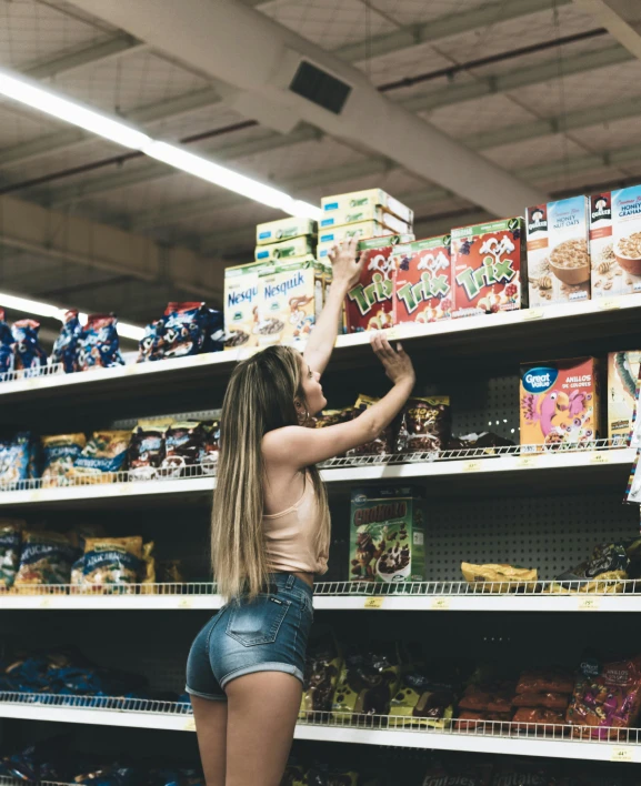 a girl trying to get some cereal from the shelves