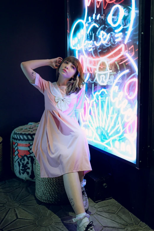 a woman in a pink dress sitting on a stool in front of a large wall painting