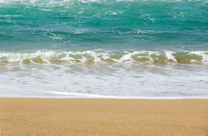 an empty surfboard on the sandy beach next to water