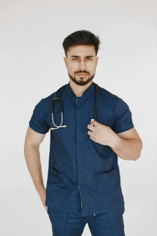 a man wearing a doctor's scrub and uniform posing for the camera