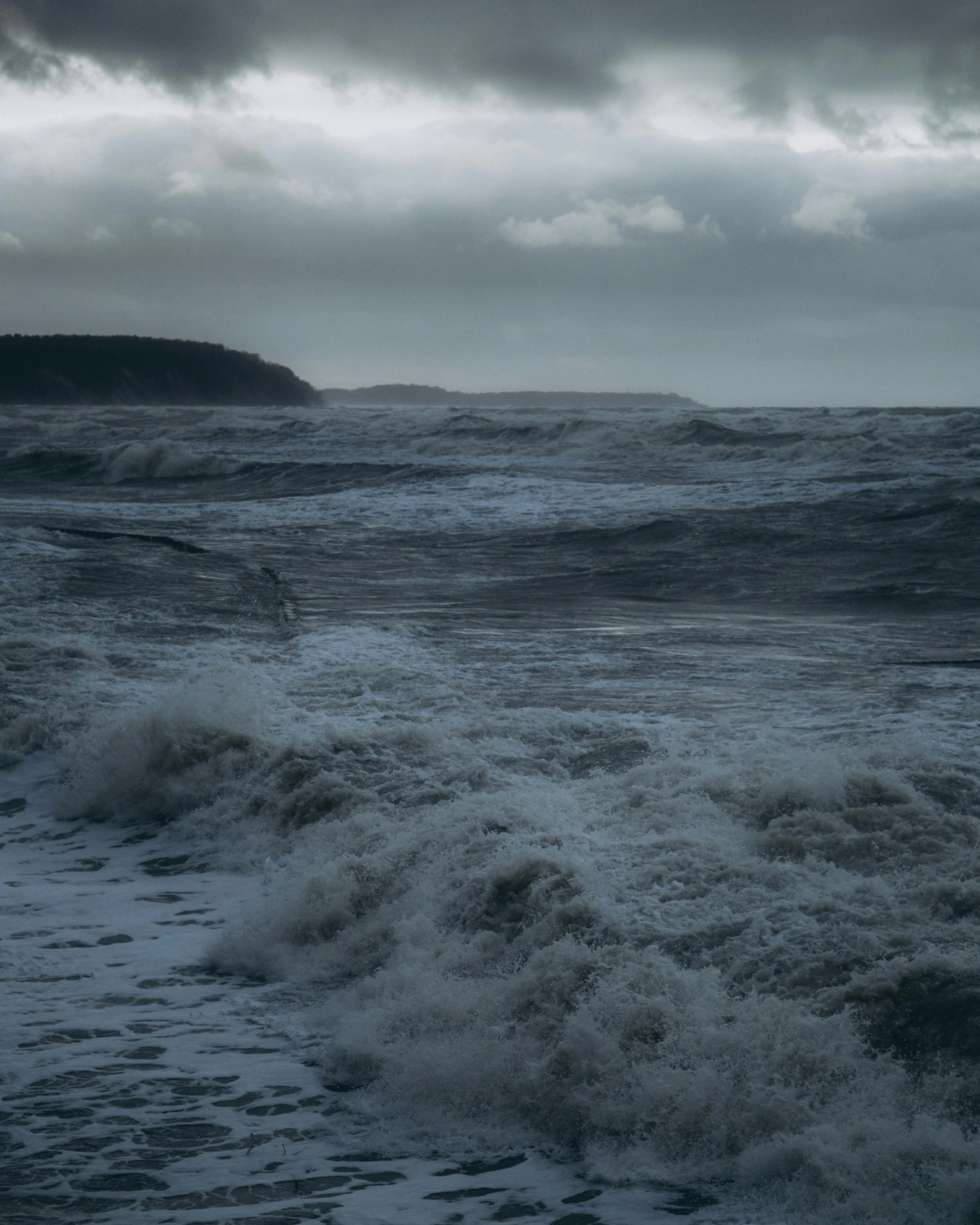 dark skies are above the ocean and some waves