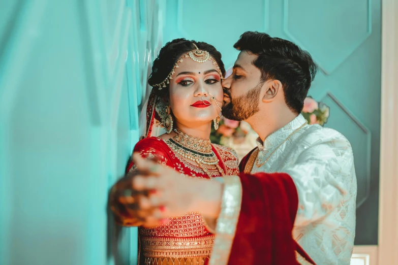 an indian bride and groom kissing in the doorway of their home