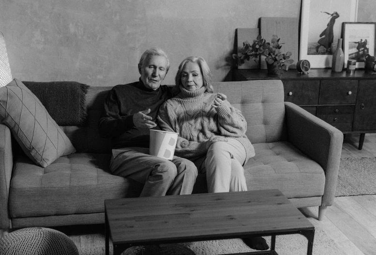 a black and white po of two people sitting on a couch