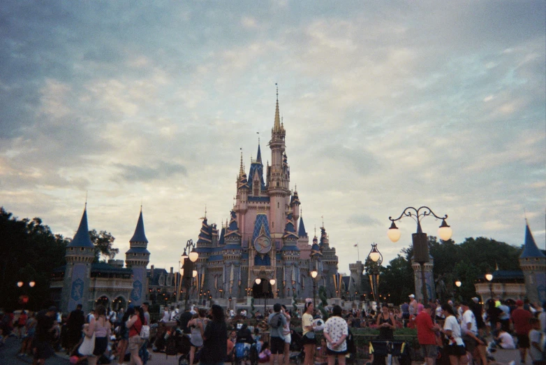 a crowd of people stand at the entrance to a disneyland park