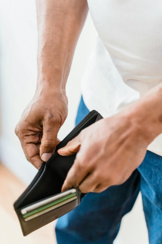 man opening an empty black purse showing it and holding it