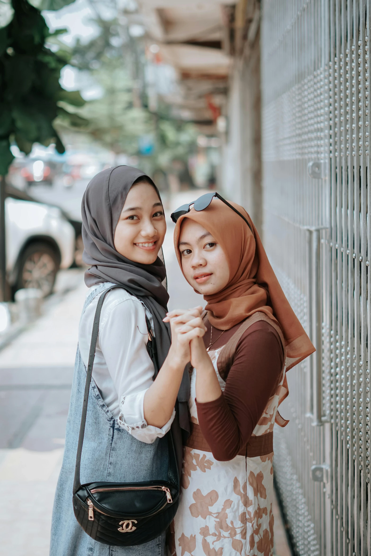 two young ladies stand next to each other by the side of the road